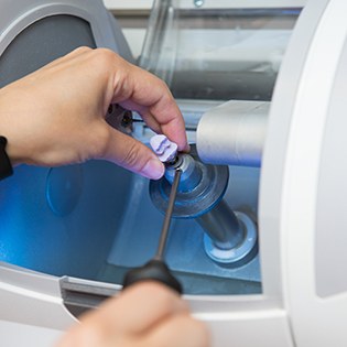 Hand removing dental crown from milling machine