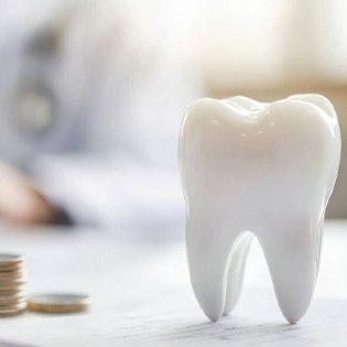 a model of a tooth next to a stack of coins