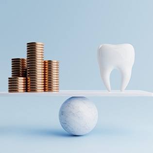 A large model tooth and stacks of golden coins on a balancing scale