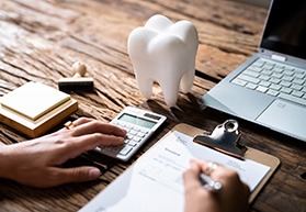 A patient using a calculator and a dental insurance form