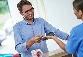 A young man paying the cost of wisdom tooth extractions